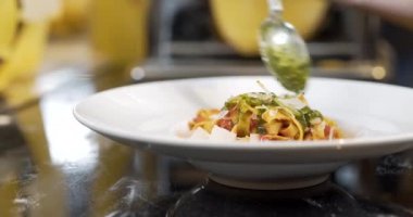 Şef makarnayı sosla süslüyor.