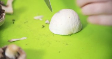 Ev hanımı mutfakta yemek pişirmek için mantar doğruyor.