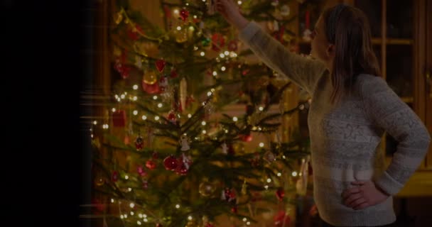 Женщина украшает рождественскую ёлку дома — стоковое видео