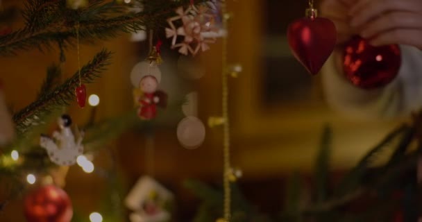 Mulher decorando árvore de Natal com bugigangas em casa. — Vídeo de Stock