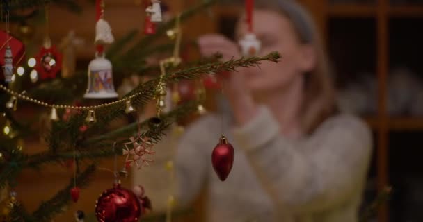 リビングルームで美しいクリスマスツリーを飾る女性。クリスマスの背景. — ストック動画