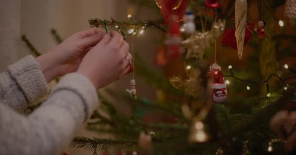 Mulher decorando árvore de Natal com bugigangas em casa. — Vídeo de Stock