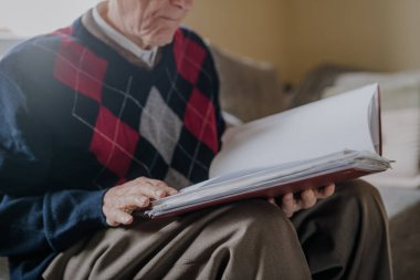 Evde kitap okuyan yaşlı bir adam.