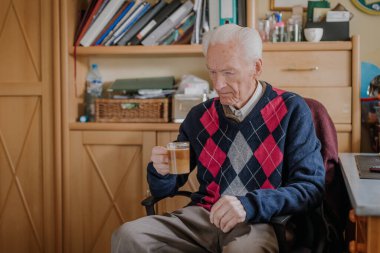 Yaşlı adam evde kahve içiyor.