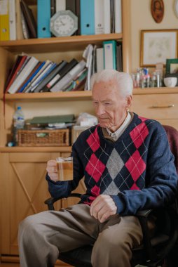 Yaşlı adam evde kahve içiyor.