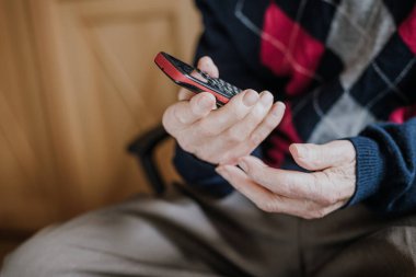 Telefonda konuşan yaşlı bir adam evde oturuyor.