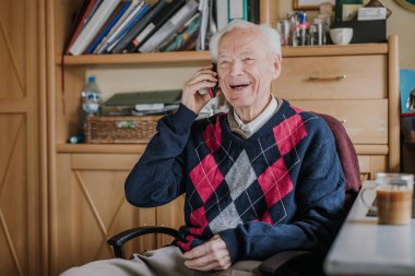 Telefonda konuşan yaşlı bir adam evde oturuyor.