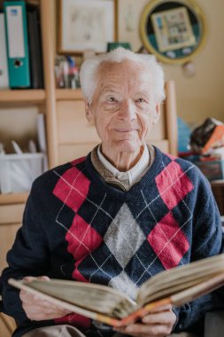 Yaşlı adam aile fotoğrafları olan eski albümlere bakıyor.