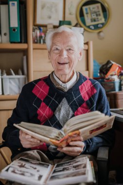 Yaşlı adam aile fotoğrafları olan eski albümlere bakıyor.