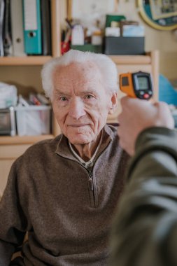 Yaşlı adam sıcaklığı termometreyle ölçtü.