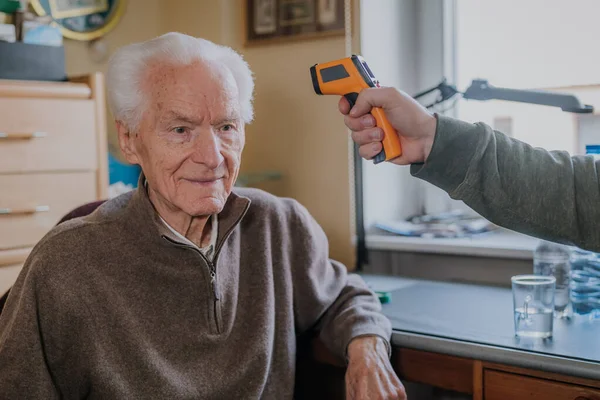 Yaşlı adam sıcaklığı termometreyle ölçtü.
