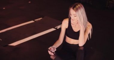Spor salonunda cep telefonu kullanan bayan sporcu.