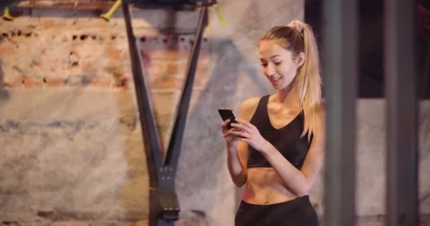 Selbstbewusste Frau nutzt Smartphone im Fitnessstudio — Stockvideo