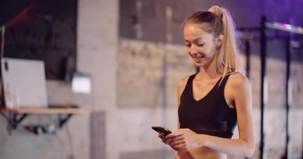 Krásná žena pomocí chytrého telefonu v tělocvičně — Stock video