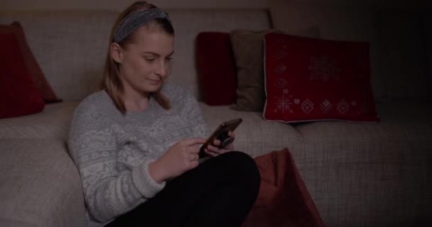 Женщина просматривает социальные сети на смартфоне дома — стоковое видео