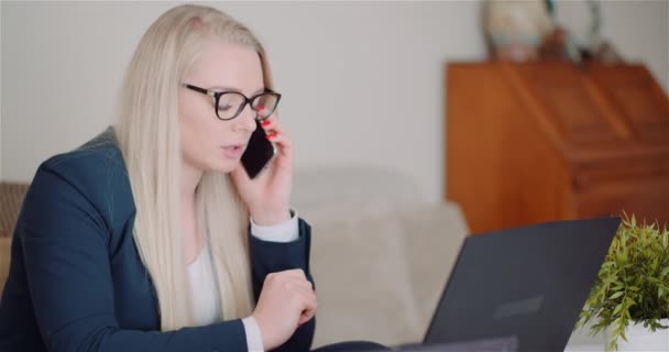 젊은 사업가가 노트북 컴퓨터를 사용하는 휴대 전화로 이야기하는 모습 — 비디오