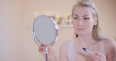 Makyaj yapan kadın maskarayla kirpiklerini boyuyor.