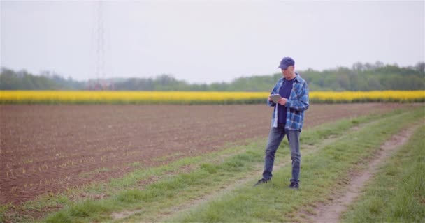Jordbrukare undersöker grödor och åkrar. Vuxenbonde Använda Digital Tablet Computer. — Stockvideo
