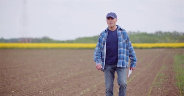 Agricultor examinando el campo agrícola mientras trabaja en la computadora digital de la tableta en la granja. — Vídeos de Stock