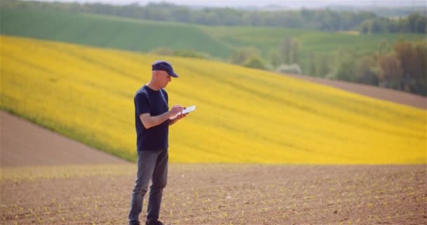 Agricultorul examinează domeniul agricol în timp ce lucrează la computerul digital de tablete la fermă . — Videoclip de stoc