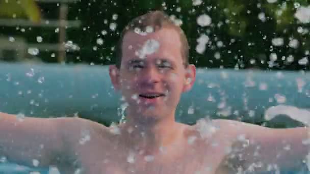 Junger Mann planscht Wasser in Pool — Stockvideo