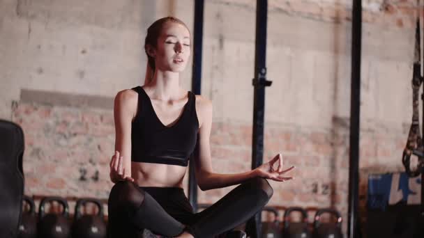 Fit junge Frau Meditieren im Fitnessstudio. Yoga im Fitnessstudio praktizieren. — Stockvideo