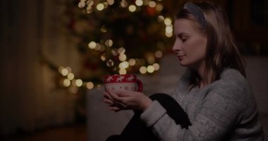 Bir fincan kahveyle evde dinlenen bir kadın.