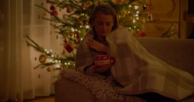 Bir fincan kahveyle evde dinlenen bir kadın.