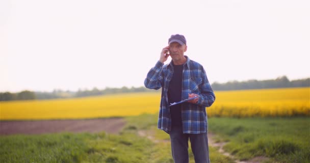 Boer praten op mobiele telefoon tijdens het werken in een veld Landbouw — Stockvideo