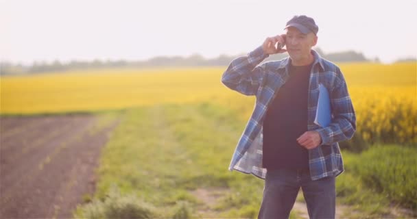 Boer praten op mobiele telefoon tijdens het werken in een veld Landbouw — Stockvideo