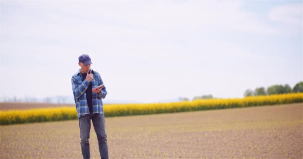 Agriculteur examinant les cultures de colza à la ferme Concept d'agriculture. — Video