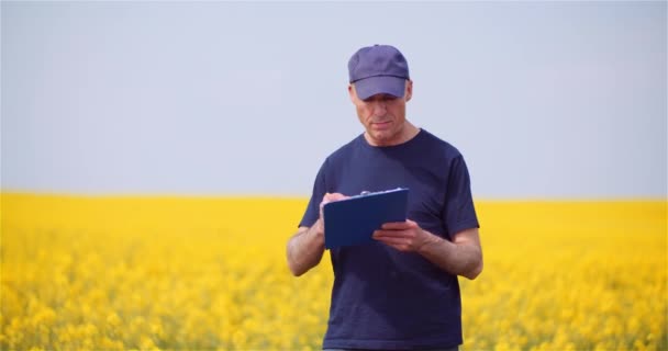 Landwirt schreibt auf Klemmbrett, während er landwirtschaftliche Flächen untersucht — Stockvideo