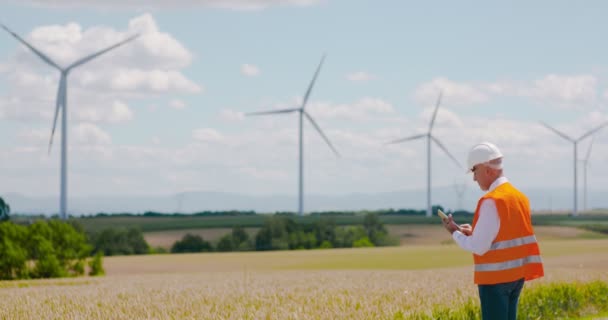 Energy Engineer working on digital tablet agains windmills farm. — Stock video