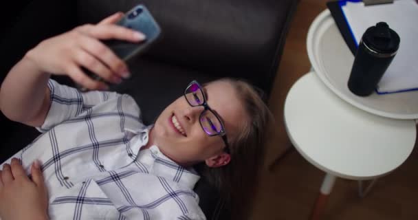 Ελκυστική επιχειρηματίας που έχει βιντεοκλήση στο κινητό τηλέφωνο, ενώ βρίσκεται στον καναπέ στο γραφείο — Αρχείο Βίντεο