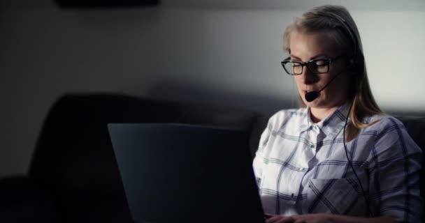 Kvindelig iværksætter ved hjælp af bærbar computer, mens du taler på headset i kontoret – Stock-video