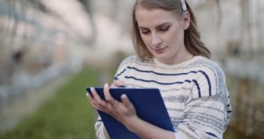 Kadın bahçıvan seradaki bitkileri inceliyor.