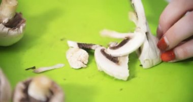 Ev hanımı mutfakta yemek pişirmek için mantar doğruyor.