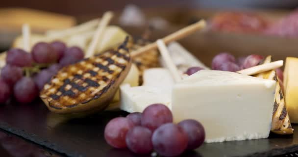 Διαφορετικοί τύποι τυριών σε ξύλινη σανίδα στο εστιατόριο — Αρχείο Βίντεο