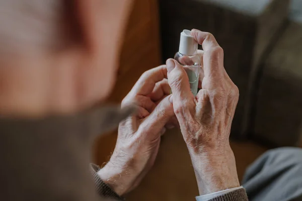 Senior désinfecte les mains avec un gel antibactérien Image En Vente