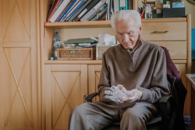 Yaşlı adam tek kullanımlık koruyucu eldivenler giyer.