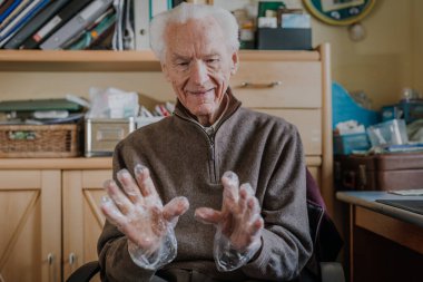 Yaşlı adam tek kullanımlık koruyucu eldivenler giyer.