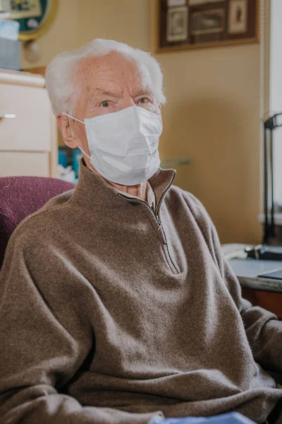 Yaşlı adam koruyucu maske ve eldiven takıyor.