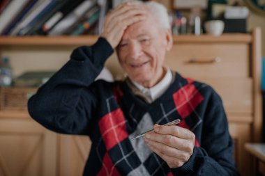 Termometreyi elinde tutan kıdemli adam - Covid-19 Konsepti.