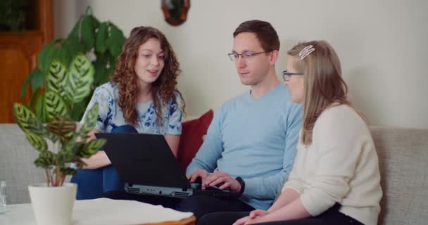 Personas exitosas trabajando en el ordenador portátil y hablando mientras están sentados en la sala de estar. — Vídeo de stock