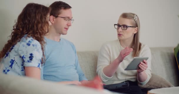 Mujer de negocios y joven pareja negocian acuerdo. Vendedora usando tableta digital durante la presentación. — Vídeos de Stock