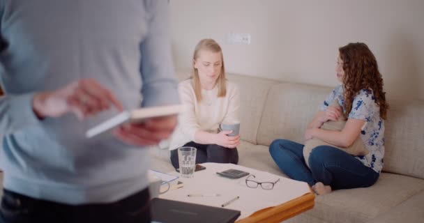 Hombre usando tableta digital en la oficina mientras dos mujeres discuten proyecto. — Vídeos de Stock