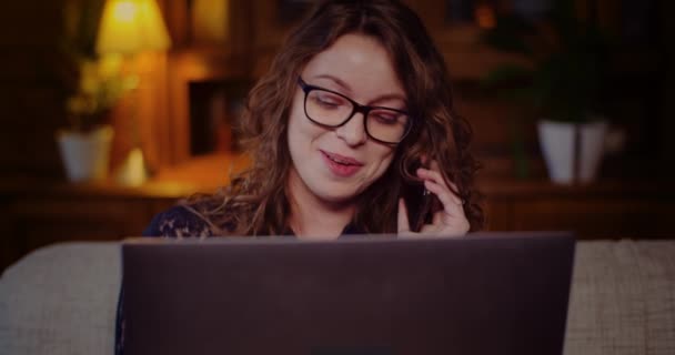 Porträt einer Geschäftsfrau, die am Laptop arbeitet, während sie mit dem Handy spricht. — Stockvideo