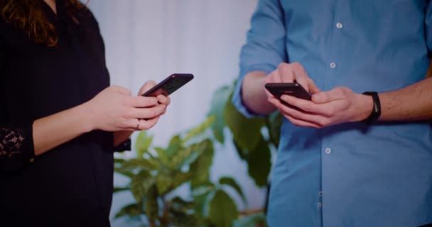 Man en vrouw typen op smartphones tijdens het hebben van een vergadering. — Stockvideo