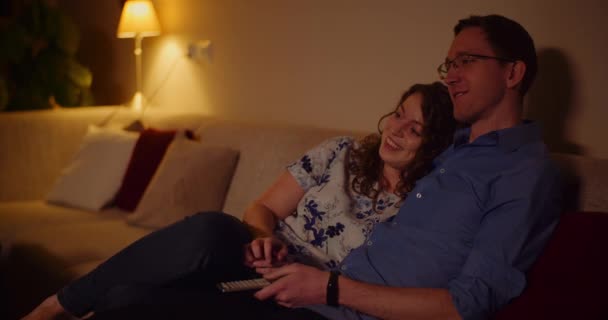 Couple Regarder la télévision à la maison Assis sur le canapé dans le salon — Video