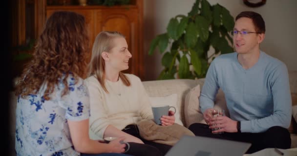 Amigos pasando tiempo juntos sonriendo y riendo mientras se sientan en el sofá en casa. — Vídeos de Stock